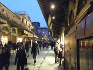 The shops along the Ponte Vecchio light up the street at dusk